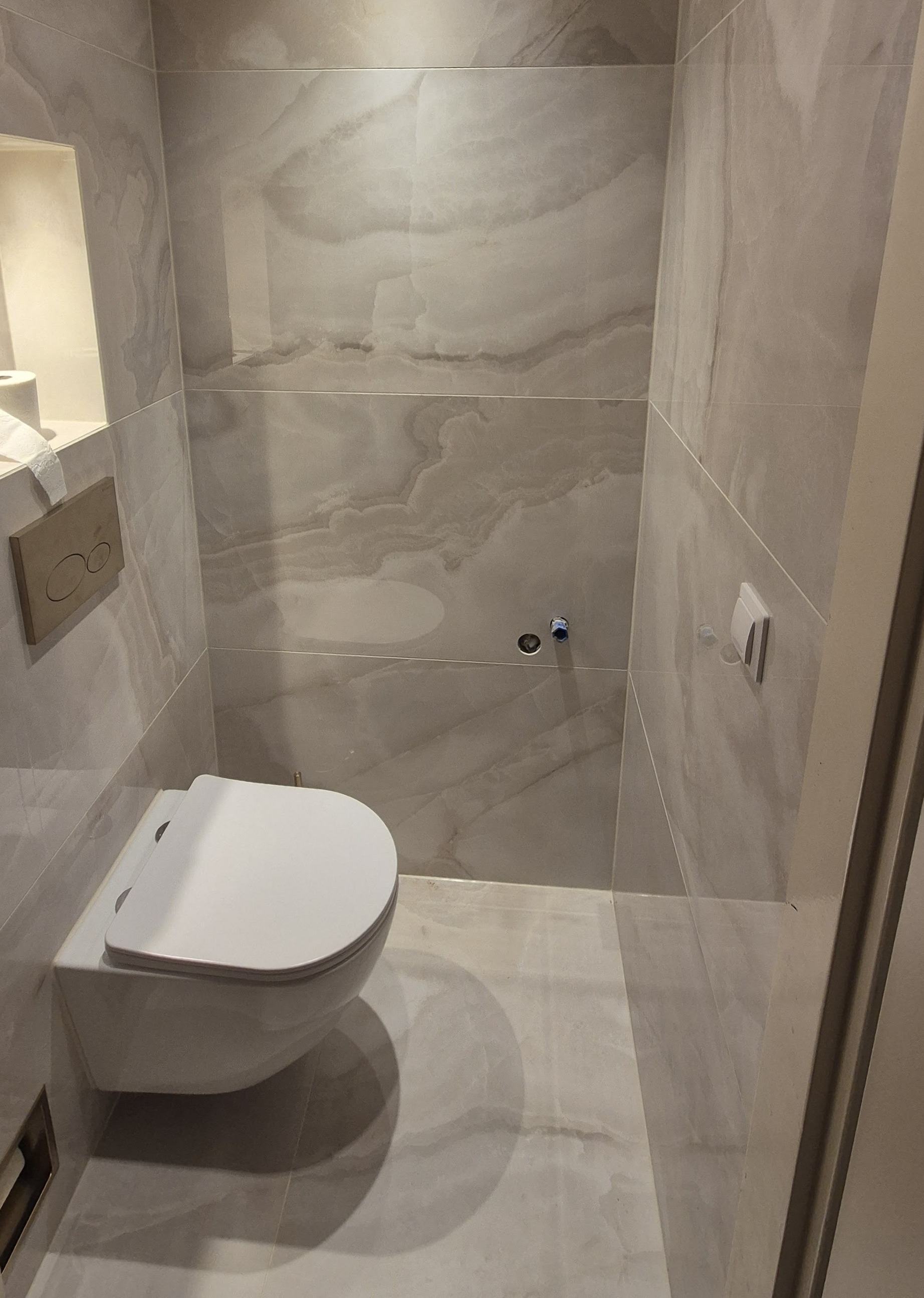 Afgewerkt toilet met hangend closet, nis en marmerlook tegels