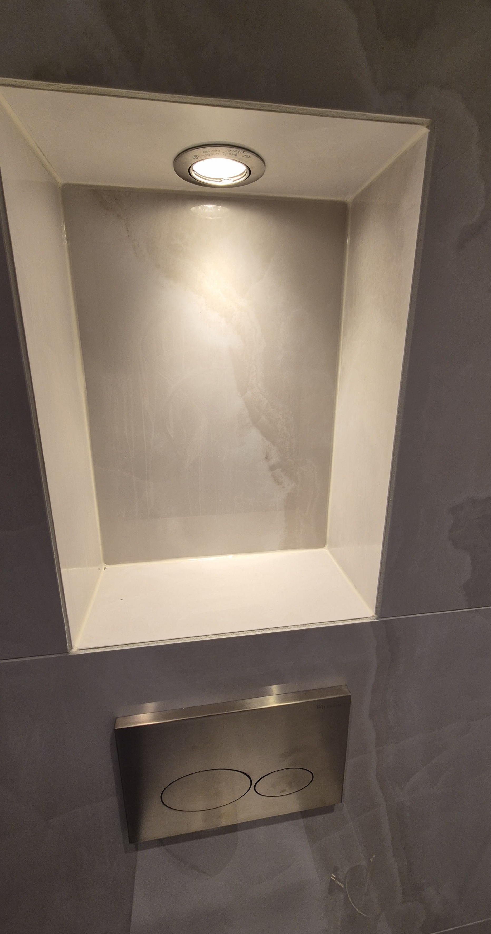 Verlichte nis boven het bedieningspaneel van het toilet, met witte kitranden